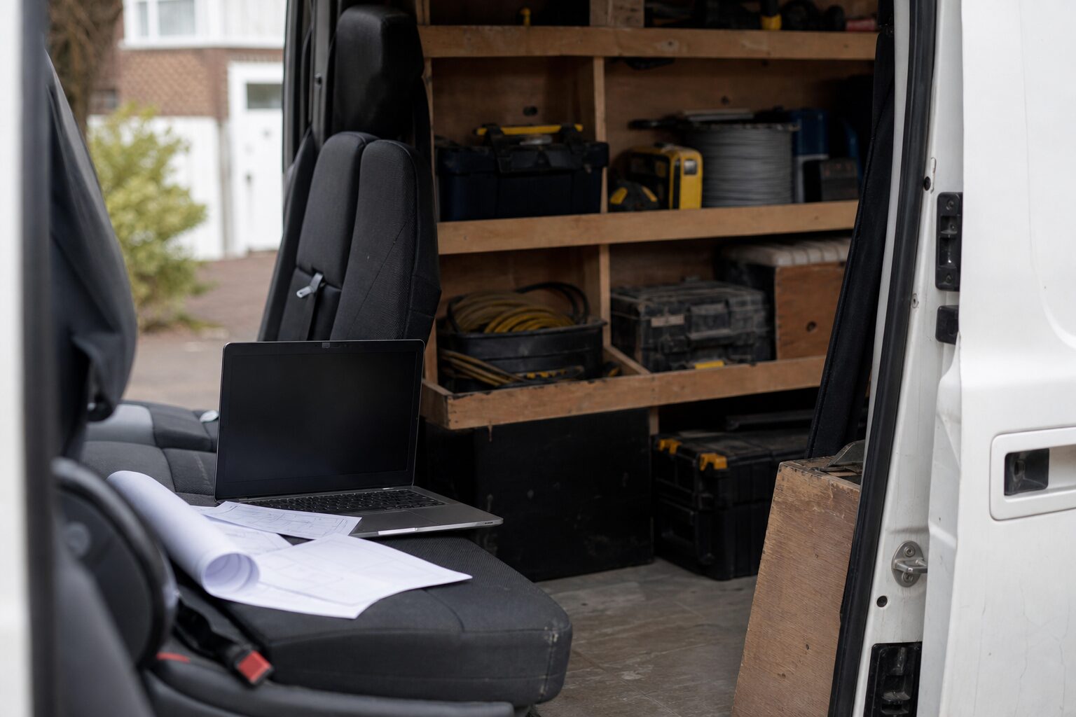 Gas engineer's van with paperwork and a laptop open on the passenger seat